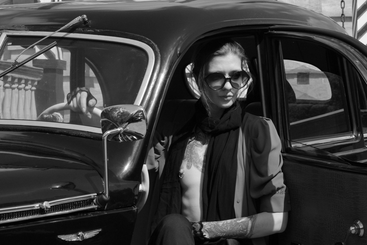 Tattooed and pierced skinny girl Lia A in an old car