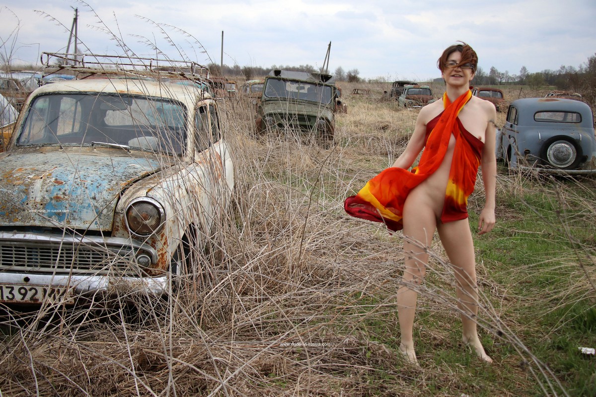 A short-haired naked girl Atisha walks through the museum of old Soviet cars