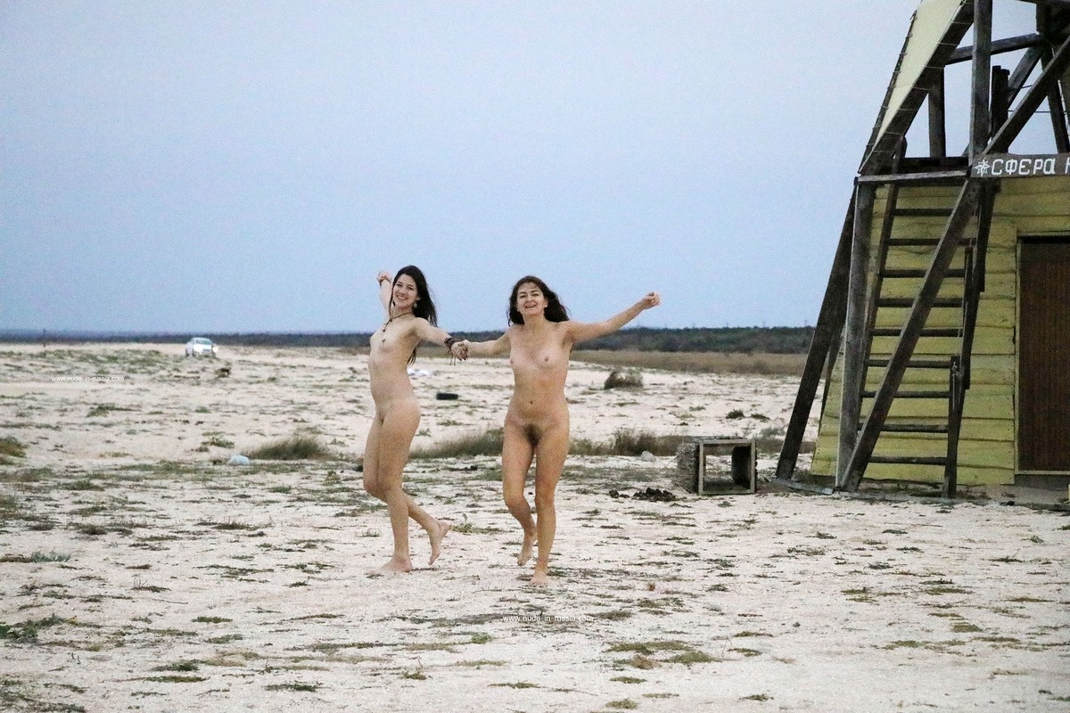 Two naked girls posing at sandy beach