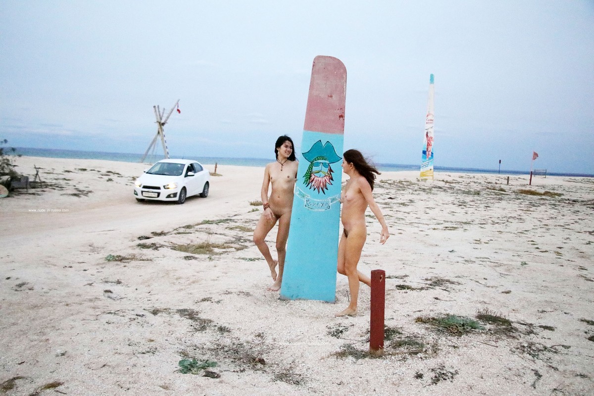 Two naked girls posing at sandy beach