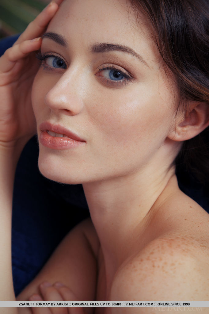 Zsanett Tormay works her alluring magic as she undresses her white sweater, posing with finesse and refinement all over the blue sofa.