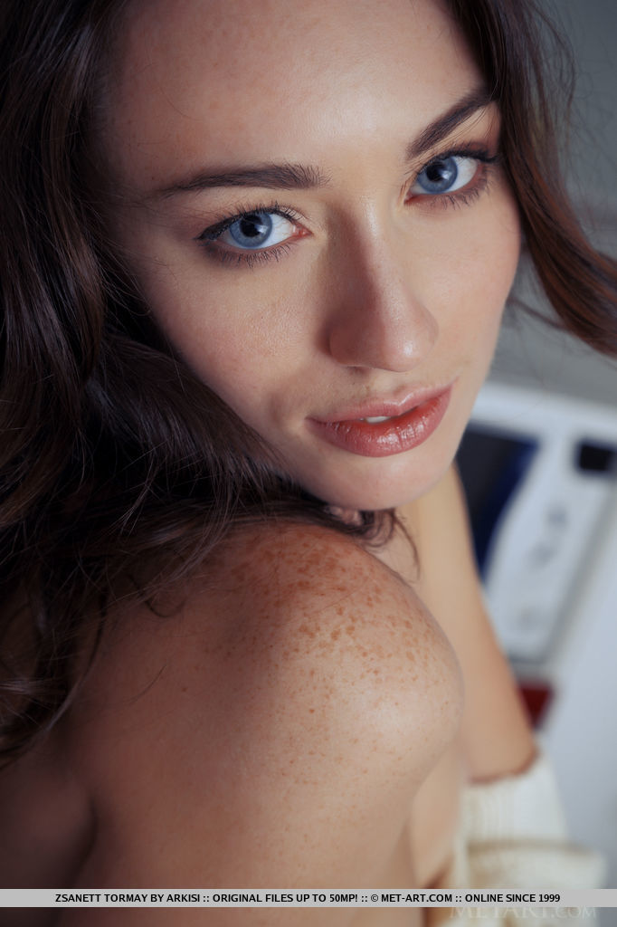 Zsanett Tormay works her alluring magic as she undresses her white sweater, posing with finesse and refinement all over the blue sofa.