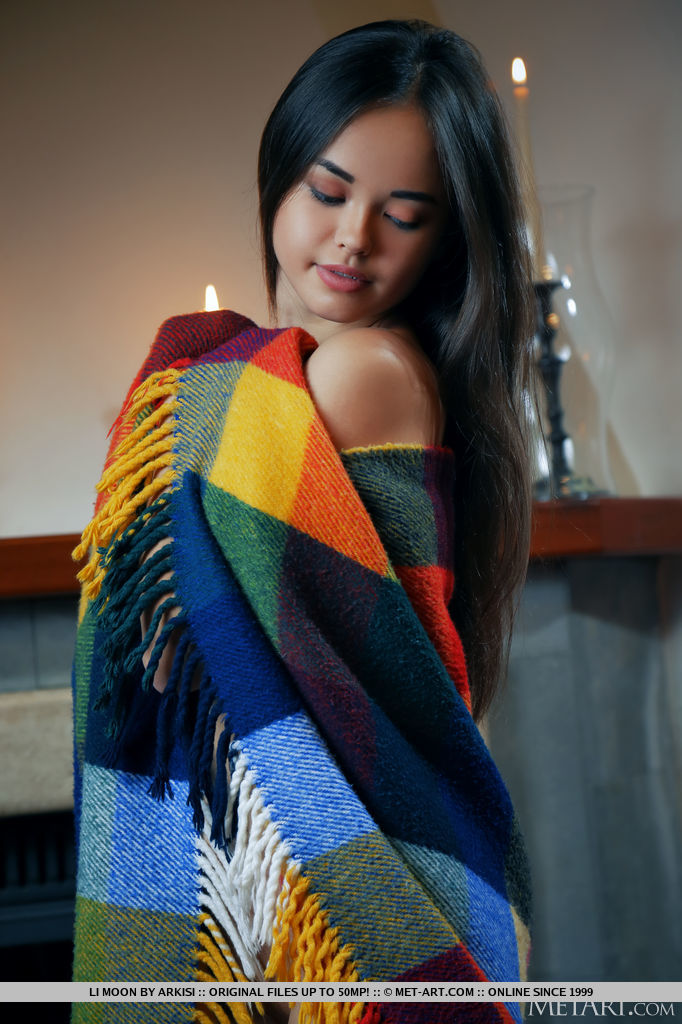 Alluring Li Moon lights up a candle stick and the fireplace to keep her naked body warm. She uses the colorful blanket to show off her juicy melons and hairless pussy.