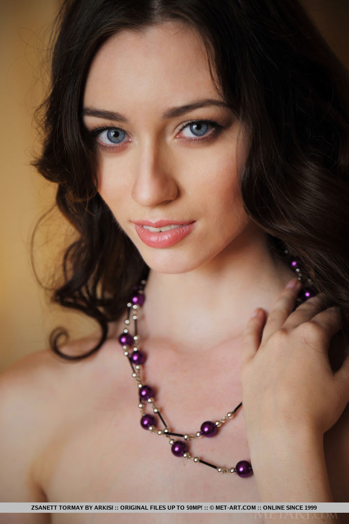 Dark, curly hair frames Zsanett Tormay's beautiful face, her sparkling blue eyes stare seductively towards the camera as she sprawls naked on top of the bed.