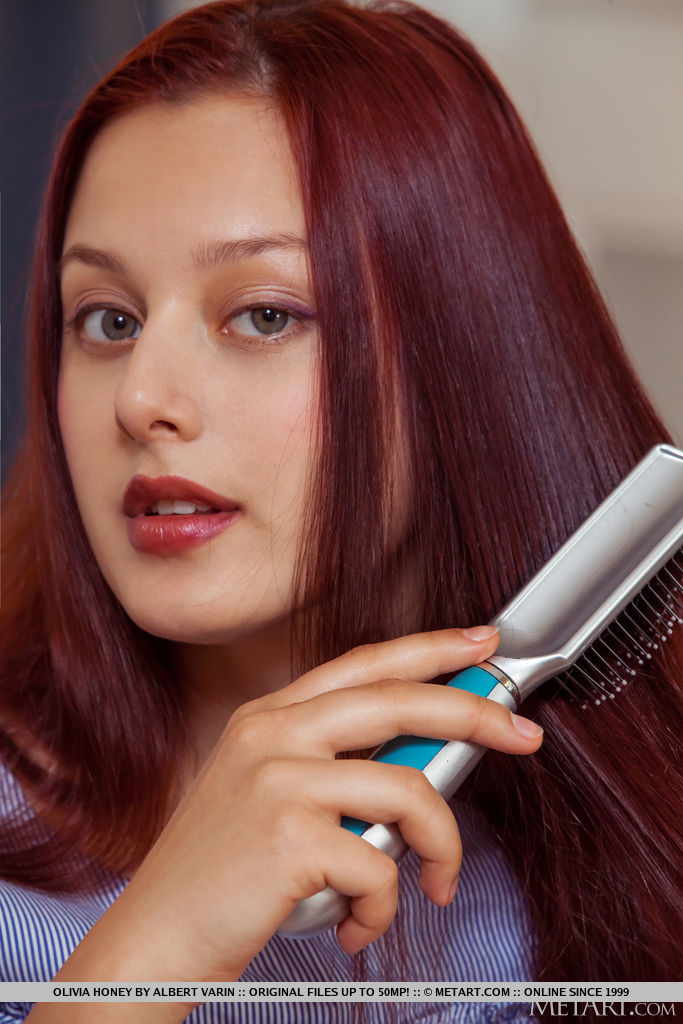 Olivia Honey brushes her red hair on the sofa and decides to divest her blue dress and flaunts her stiff nipples and shaved pussy.