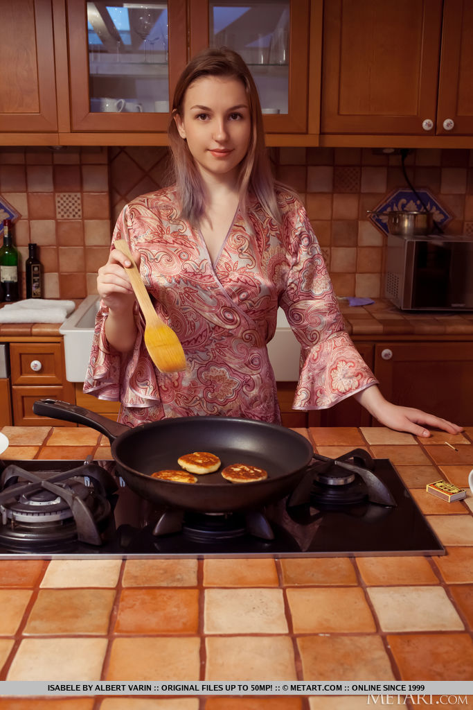 Isabele cooks pancakes in the kitchen and decides to disrobe, sits with open legs on the sofa and shows off her moist pinkish hairless coochie.