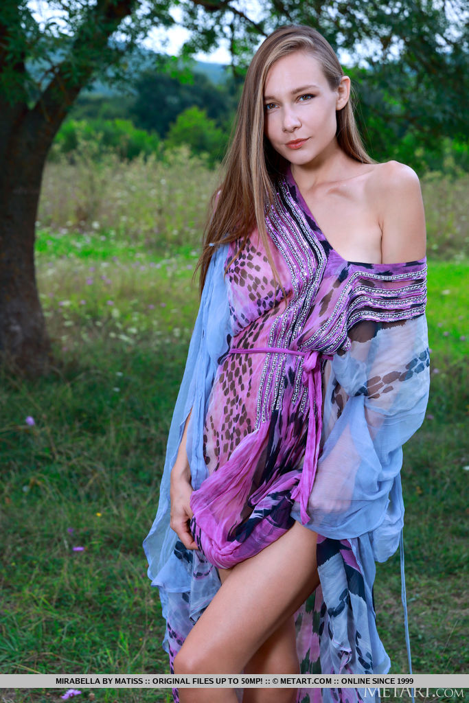Mirabella removes her flowy sheer robe and exposes her soft bumtastic figure and hairless cunt on the field.